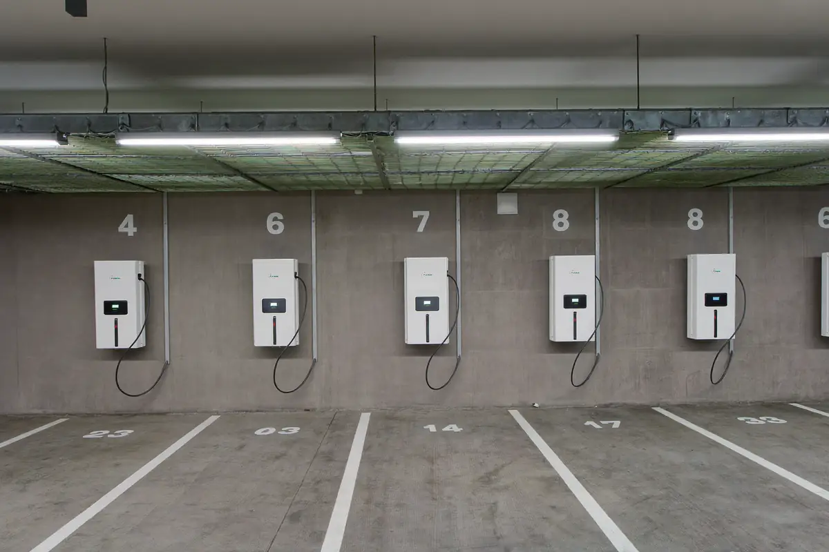 Fila de carregadores numa garagem de prédio ligados por uma esteira de cabos